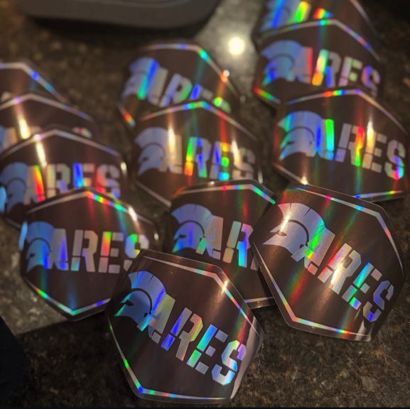 A collection of multicolored holographic stickers with the word 'ARES' displayed and sitting on a countertop