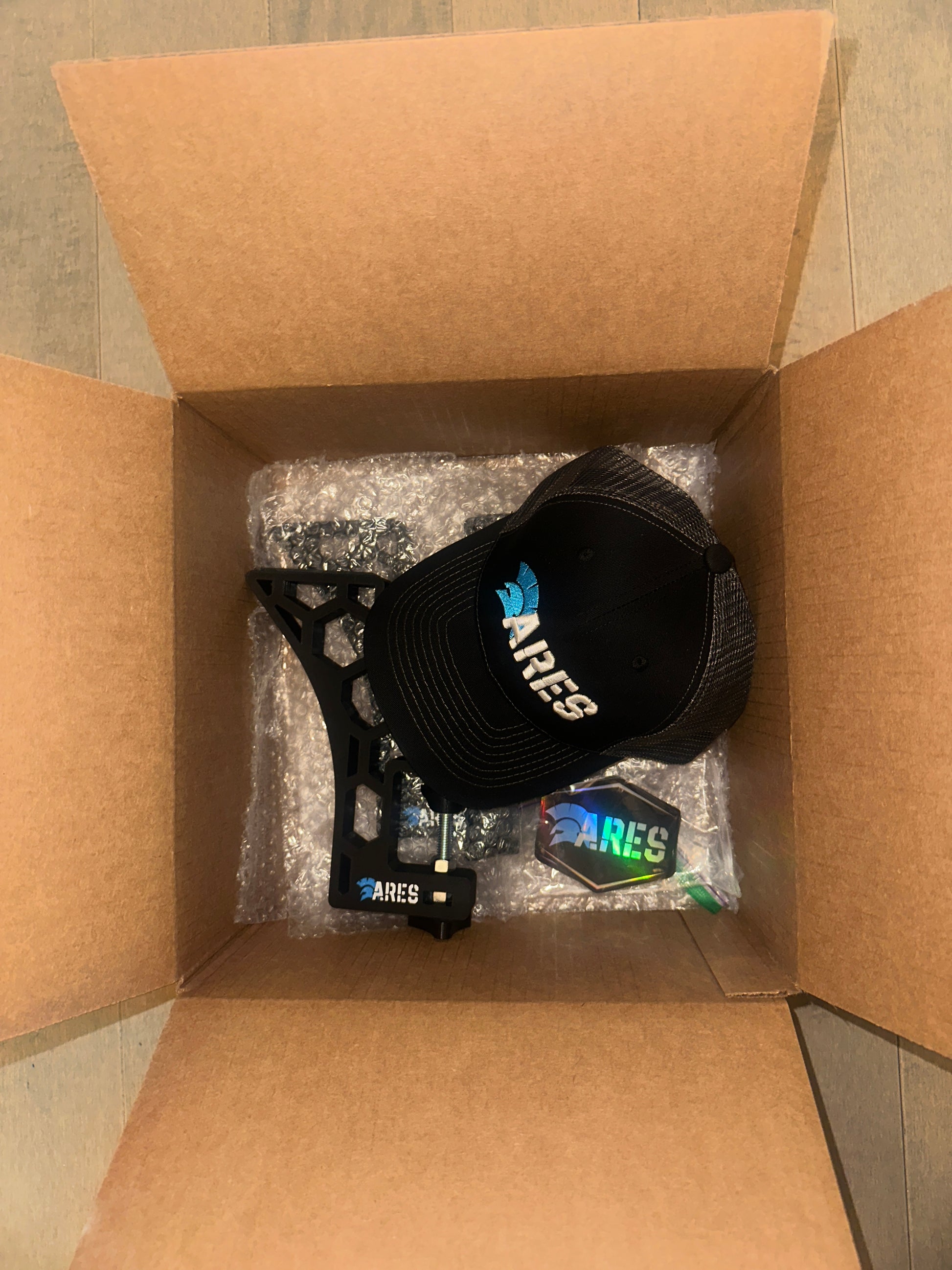 Shipment of Ares products containing eco snowboarding wax, snowboard tuning and waxing stands/vices, holographic stickers and an ares trucker hat