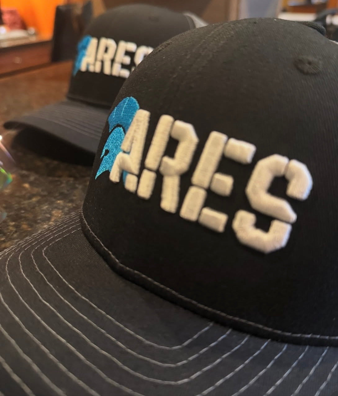 Two black caps with 'ARES' branding on a countertop